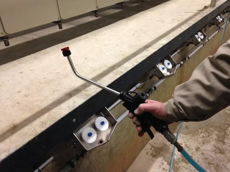 Handheld teat spray applicator in dairy parlour